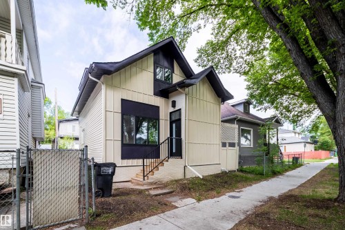 Modern dwelling with a prominent gable roof, light-colored vertical siding, and dark trim accents - 10866 92 Street, Edmonton, AB 