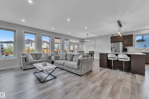 Open-concept living space featuring wood-finish flooring, recessed lighting, and multiple windows - 17551 64 Street, Edmonton, AB 