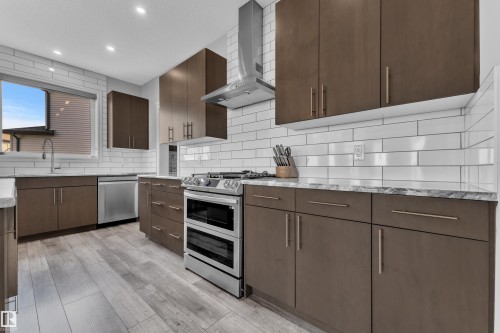 Modern kitchen featuring wood-finish cabinetry, stainless steel appliances, and light-toned countertops - 17551 64 Street, Edmonton, AB 