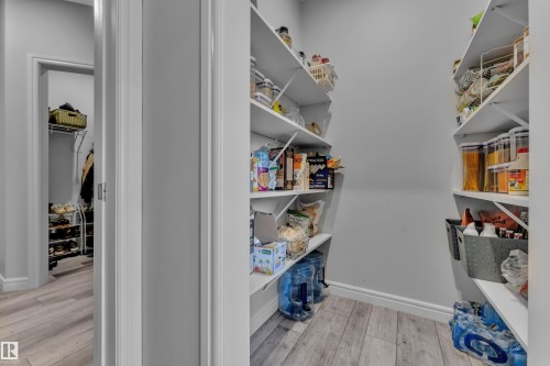 Walk-in pantry featuring extensive built-in shelving, light wood-finish flooring, and crisp white trim - 17551 64 Street, Edmonton, AB 
