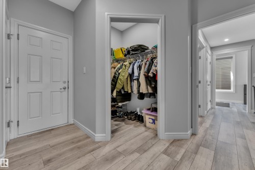 Entryway featuring wood-finish flooring, a white paneled door, and a recessed closet with built-in wire shelving - 17551 64 Street, Edmonton, AB 