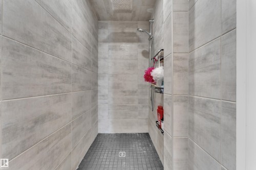 Shower stall with light gray rectangular wall tiles, a ceiling-mounted rainfall showerhead, and a handheld shower fixture - 17551 64 Street, Edmonton, AB 