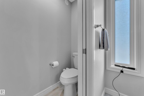 Powder room featuring a white toilet, light gray walls, and a recessed ceiling light - 17551 64 Street, Edmonton, AB 