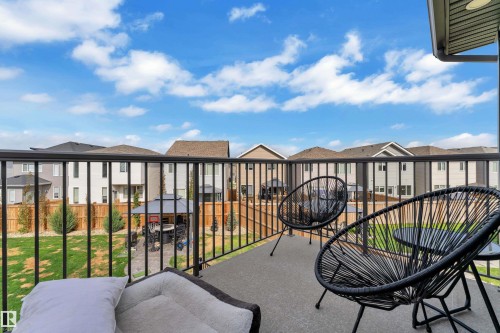 Concrete balcony with black metal railings overlooking a backyard with green lawn and wooden fencing - 17551 64 Street, Edmonton, AB 