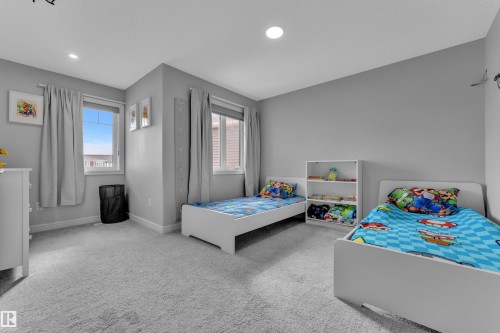 Spacious room featuring light grey carpeting and two windows with blinds and drapery - 17551 64 Street, Edmonton, AB 