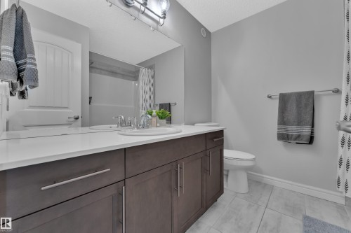 Bathroom featuring a dual-sink vanity with dark wood-finish cabinetry, white countertop, and chrome fixtures - 17551 64 Street, Edmonton, AB 