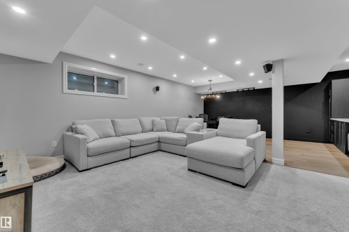 Open-concept recreation room featuring recessed lighting, light gray carpet flooring, a window with white trim, and a wood-finish flooring area - 17551 64 Street, Edmonton, AB 