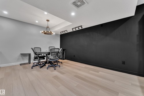 Spacious room featuring light wood-finish flooring, a dark accent wall, and recessed ceiling lighting - 17551 64 Street, Edmonton, AB 