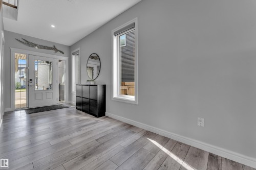 Entryway featuring wood-finish flooring, white trim, and a white front door with sidelight windows - 17551 64 Street, Edmonton, AB 