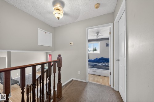 Second-story landing with wood-finish railing and balusters, featuring a ceiling-mounted light fixture - 2832 35 Street, Edmonton, AB 