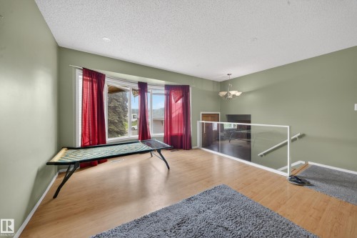 Light wood-finish flooring complements the bay windows with red drapery - 2832 35 Street, Edmonton, AB 