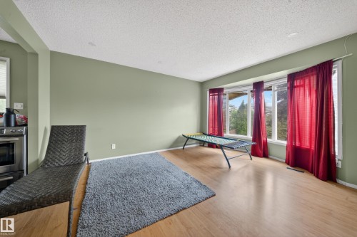 Bright interior space featuring a multi-pane bay window, recessed ceiling lighting, light wood-finish flooring, and a portion of a stainless steel range - 2832 35 Street, Edmonton, AB 