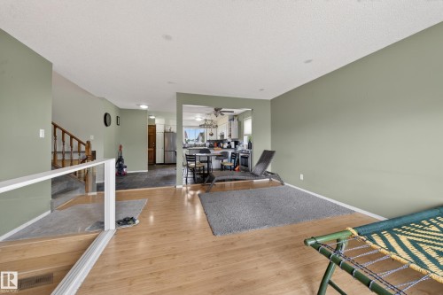 Bright interior featuring wood-finish flooring, a kitchen with stainless steel appliances, and a staircase with a wooden banister - 2832 35 Street, Edmonton, AB 