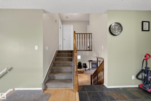 Split-level entry featuring a carpeted staircase with wood banister - 2832 35 Street, Edmonton, AB 