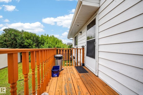 Exterior deck featuring wood-finish flooring, a wood baluster railing, and direct access to the interior via a glass-panel door - 2832 35 Street, Edmonton, AB 