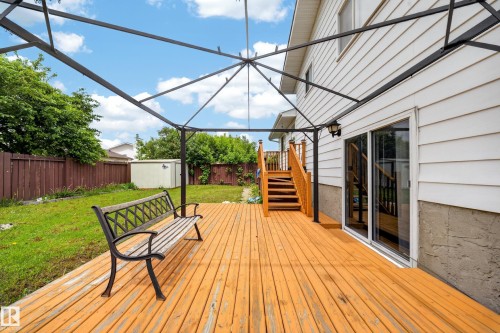 Spacious wood-finish deck with an integrated pergola frame, wood staircase, and sliding glass door access - 2832 35 Street, Edmonton, AB 