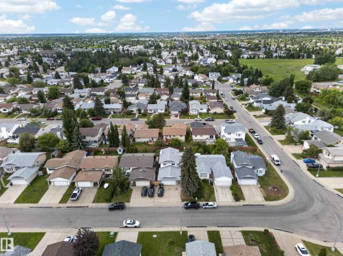 Aerial perspective showcasing a residential neighborhood with diverse single-family homes, mature trees, paved streets, and a prominent green space - 2832 35 Street, Edmonton, AB 
