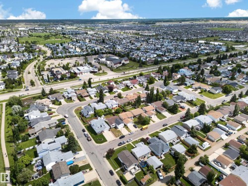 Expansive aerial perspective showcasing a residential development with diverse housing styles, mature landscaping, paved roadways, and integrated commercial properties - 2832 35 Street, Edmonton, AB 