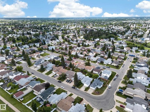 Expansive aerial perspective showcasing a residential neighborhood with numerous single-family homes, mature trees, paved streets, and a clear sky with scattered clouds - 2832 35 Street, Edmonton, AB 