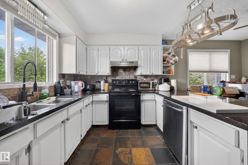 Kitchen featuring white cabinetry, dark countertops, and slate tile flooring - 2832 35 Street, Edmonton, AB 