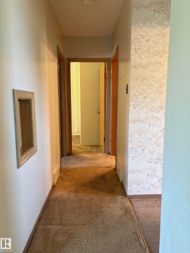Hallway featuring light tan carpeting and white baseboards - 5511 50 St, Tofield, AB 