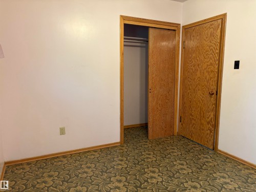 Room featuring patterned carpet, light-toned walls, and wood-finish trim - 5511 50 St, Tofield, AB 