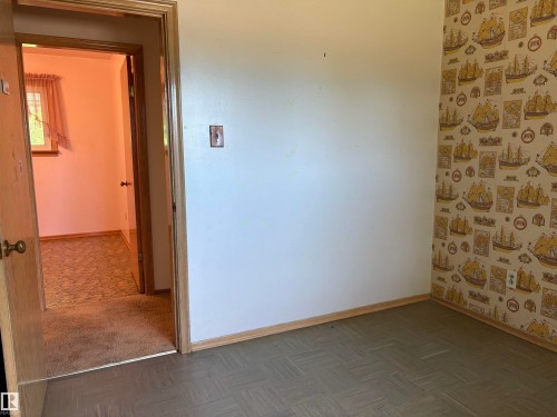 Room featuring two-tone wall treatment with a neutral painted wall and a patterned wallpaper accent wall - 5511 50 St, Tofield, AB 