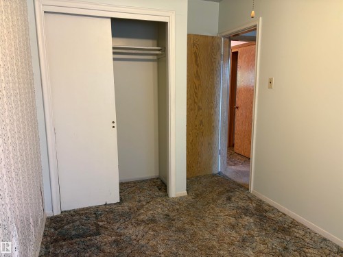 Bedroom featuring a double-door closet with sliding panels and interior hanging rods - 5511 50 St, Tofield, AB 