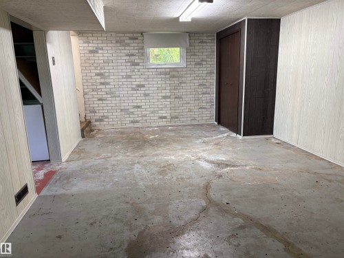 Finished basement space featuring a window, light-toned brick-patterned wall, and two-tone paneling - 5511 50 St, Tofield, AB 