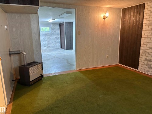 Interior space featuring green carpeting and a wall-mounted sconce - 5511 50 St, Tofield, AB 