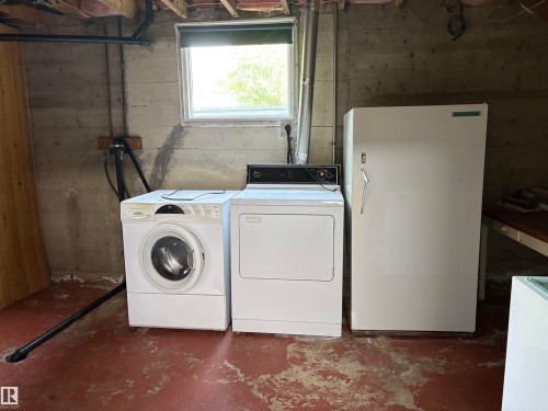 Laundry area featuring a front-load washing machine, a dryer, and a stand-up freezer - 5511 50 St, Tofield, AB 