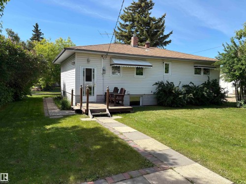 Exterior featuring light-colored siding and a brown shingle roof - 5511 50 St, Tofield, AB 
