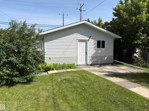 Detached garage featuring white vinyl siding, a white entry door, and a single window - 5511 50 St, Tofield, AB 