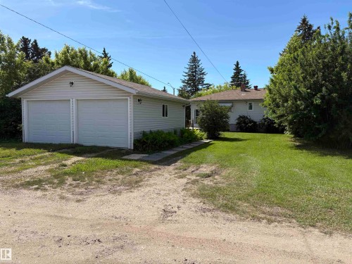 Detached two-car garage with white vinyl siding and dual overhead doors - 5511 50 St, Tofield, AB 