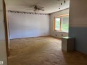 Spacious interior room featuring a large bay window, ceiling fan, and carpeted flooring - 5511 50 St, Tofield, AB 