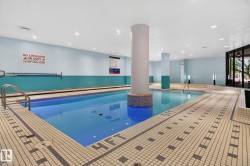 Indoor swimming pool featuring light blue walls, recessed lighting, and large windows - 