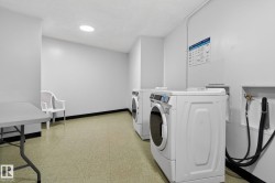 Dedicated laundry area featuring a white front-loading washing machine, light-colored flooring, and a round overhead light fixture - 