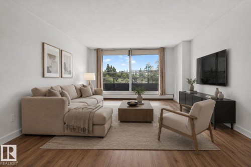 Spacious living area featuring expansive windows, wood-finish flooring, crisp white walls, and a private outdoor balcony - 412 13910 Stony Plain Road, Edmonton, AB 