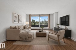 Spacious living area featuring expansive windows, wood-finish flooring, crisp white walls, and a private outdoor balcony - 