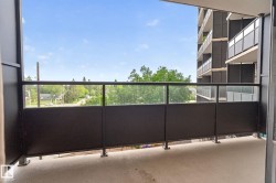 Private balcony featuring a concrete floor, black metal railings, and clear glass panels - 