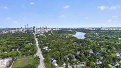 Expansive aerial perspective showcasing a cityscape, a winding river with a bridge, and a broad tree-lined road - 