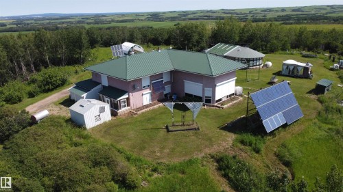 Property featuring a green metal roof, multiple solar panel arrays, and an additional round outbuilding - 55419 Rr73, Rural St. Paul County, AB 