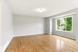 Spacious room featuring wood-finish flooring, light grey wall tones, and white trim - 