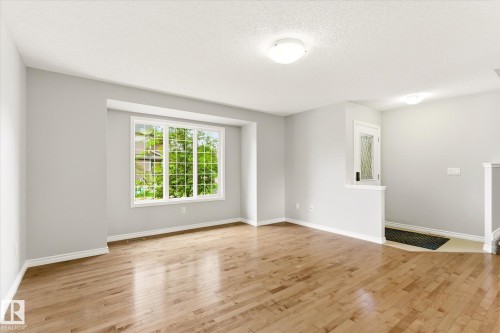 Living area featuring hardwood flooring, a large multi-pane window, light gray wall paint, and white trim - 9039 219 Street, Edmonton, AB 