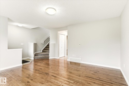 Hardwood-style flooring throughout a spacious room with light-toned walls - 9039 219 Street, Edmonton, AB 
