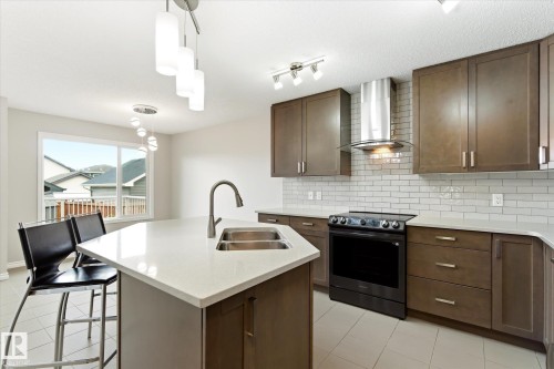 Modern kitchen featuring a central island with an undermount double sink and gooseneck faucet - 9039 219 Street, Edmonton, AB 