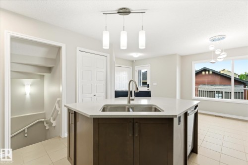Kitchen island featuring a double-basin sink and integrated dishwasher - 9039 219 Street, Edmonton, AB 