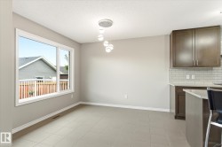 Open-concept living space with large window, tile flooring, contemporary pendant lighting, and kitchen island with seating - 