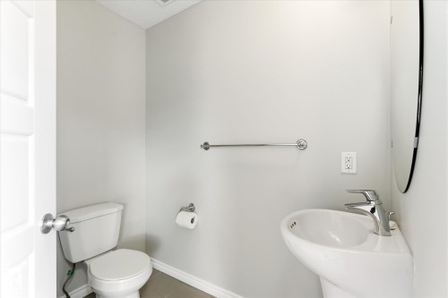 Pedestal sink with chrome faucet, complemented by a contemporary wall mirror - 9039 219 Street, Edmonton, AB 