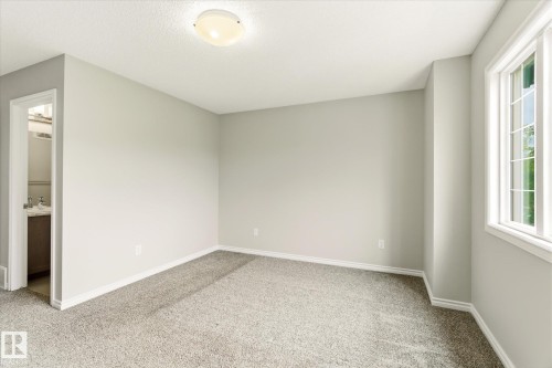 Carpeted room featuring light gray walls, white trim, and a multi-pane window - 9039 219 Street, Edmonton, AB 